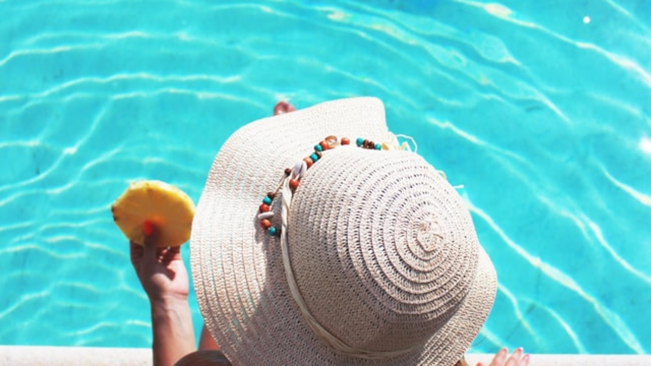 woman eating a slice of pineapple next to a pool