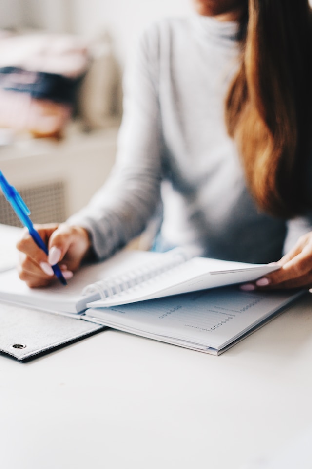 women writing on some documents with a pen