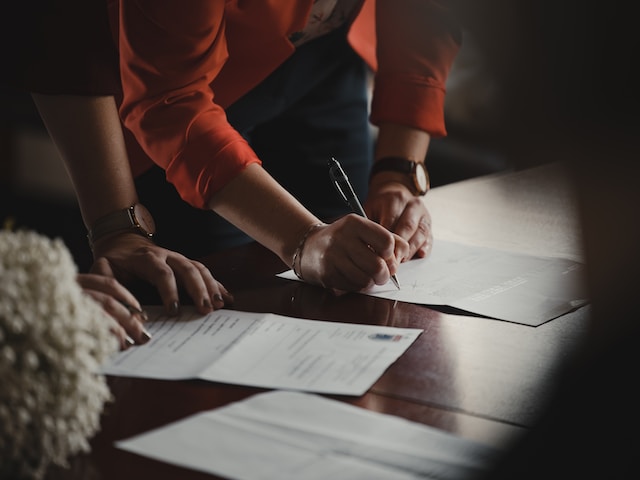 person signing a document at an office table